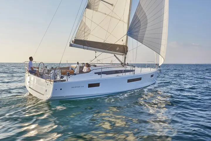 Jeanneau Sun Odyssey 410: under sail on calm sea, two people in the cockpit with twin helm wheels and white sails