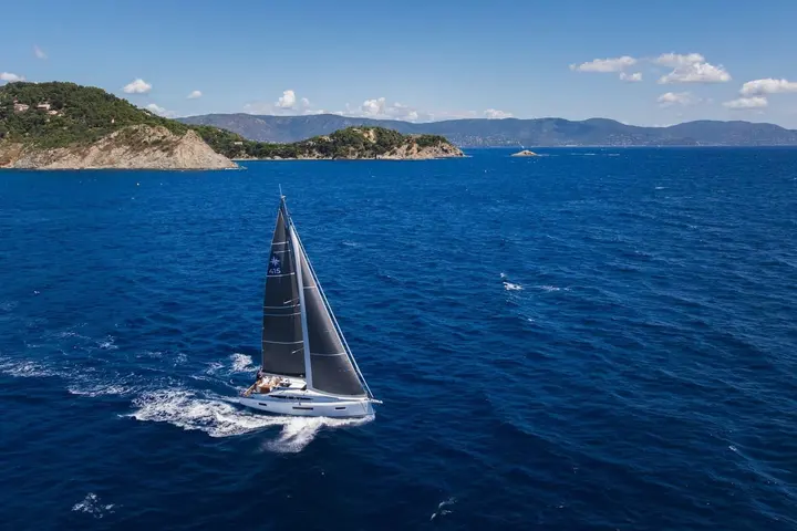 Jeanneau Sun Odyssey 415: sailing on deep blue water past wooded rocky headlands, sails trimmed close to the wind