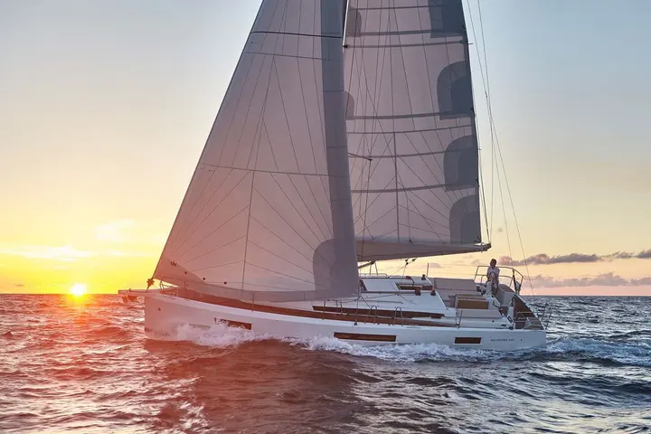 Jeanneau Sun Odyssey 440: sailing at sunset under full mainsail and genoa, white hull with long hull windows