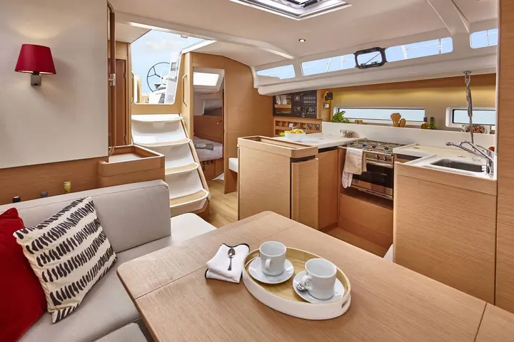Jeanneau Sun Odyssey 440: saloon in light oak with dining table, companionway steps and galley with oven and sink