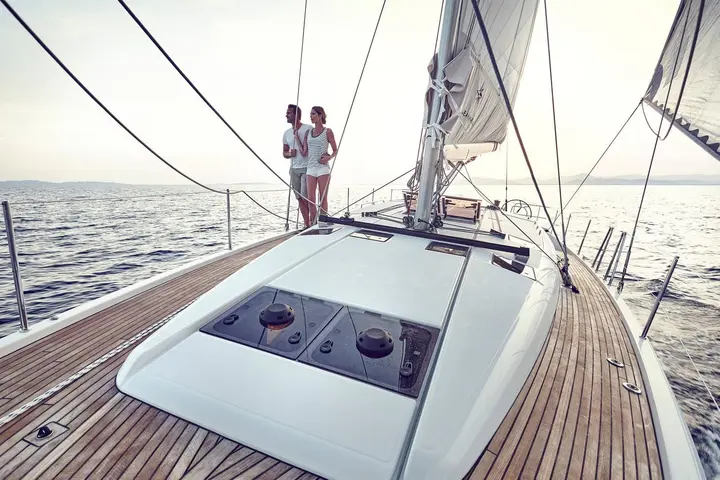Jeanneau Sun Odyssey 490: teak foredeck with hatches on the coachroof, a couple standing by the mast under sail