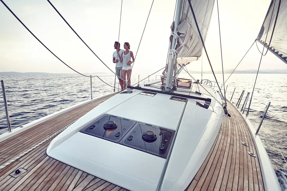 Jeanneau Sun Odyssey 490: teak foredeck with hatches on the coachroof, a couple standing by the mast under sail