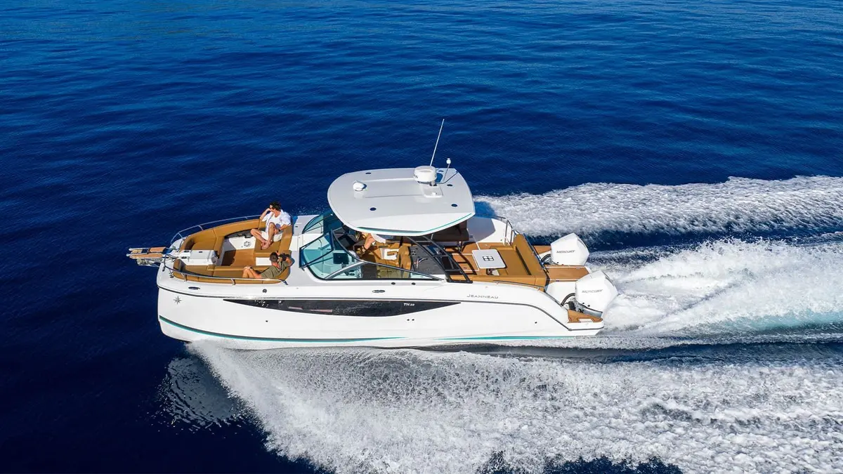 Jeanneau TH33: aerial view of the boat under way at speed, white hull, hardtop and twin outboard engines leaving wake