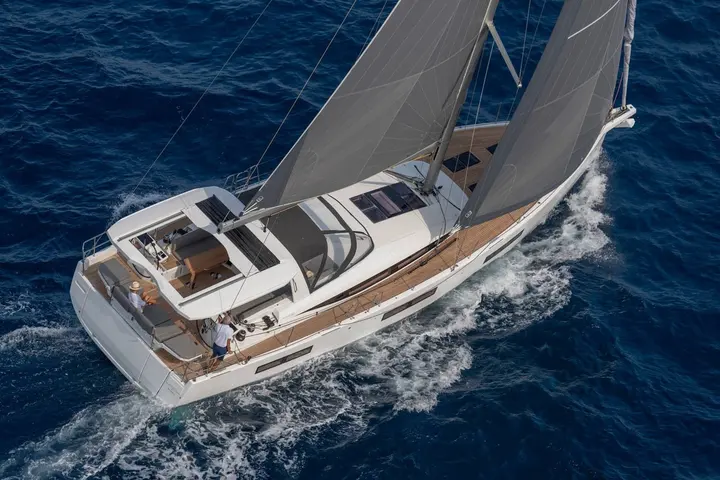 Jeanneau Yachts 60: overhead view under full sail, cockpit with table and lounging cushions, crew at helm