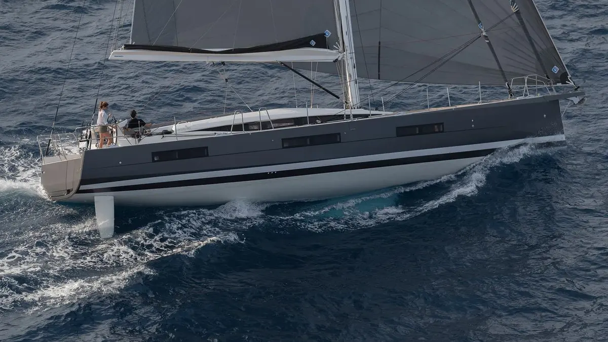 Jeanneau Yachts 60: yacht under sail heeling slightly, dark grey hull topsides, two people in the cockpit