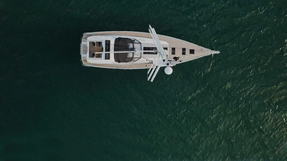 Jeanneau Yachts 65: aerial view from above of the yacht on dark green water, showing teak decks and cockpit