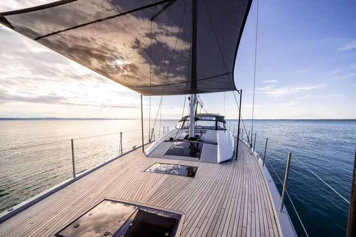 Jeanneau Yachts 65: teak foredeck with flush hatches under a shade awning, looking aft towards the mast and coachroof