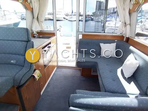 Nimbus 310 Coupe: saloon looking aft to patio door, with blue U-shaped seating and galley to port