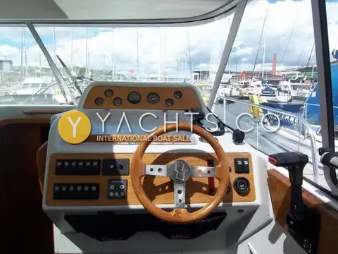 Nimbus 310 Coupe: starboard helm with wooden wheel, gauges, switch panel and throttle lever beside windscreen