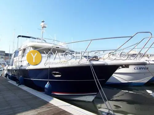 Nimbus 380 Commander Reduced: navy blue hull with white superstructure and flybridge, moored stern-in on a marina pontoon