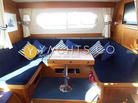 Nimbus 380 Commander Reduced: saloon with navy U-shaped seating, striped cushions, folded teak table and wall-mounted TV