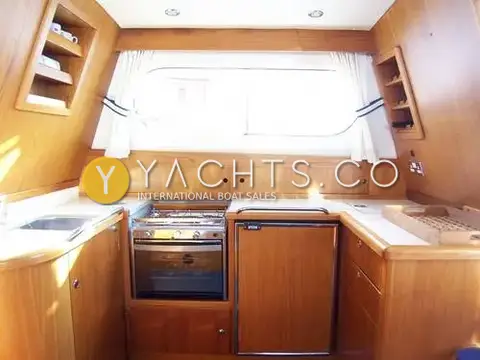 Nimbus 380 Commander Reduced: galley with teak cabinetry, sink, gas hob and oven, and integrated fridge
