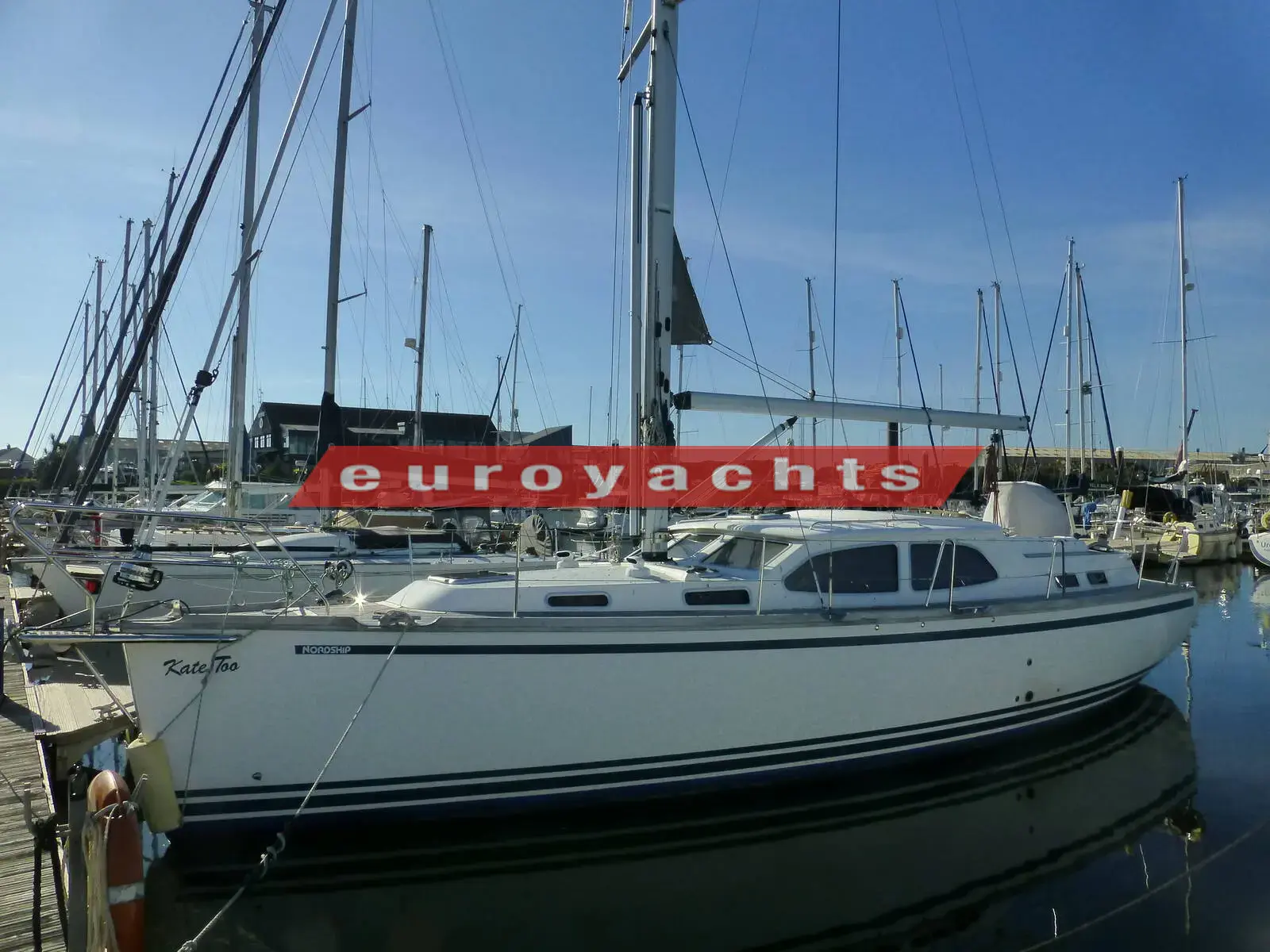 Nordship 380 DS: starboard side of the white deck saloon hull moored in a sunny marina