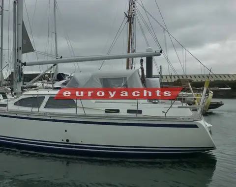 Nordship 380 DS: port side in a marina under grey skies, cockpit canopy fitted