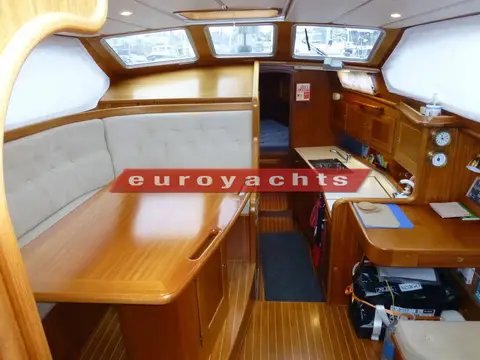 Nordship 380 DS: saloon with raised seating, teak table and chart table, panoramic deck saloon windows