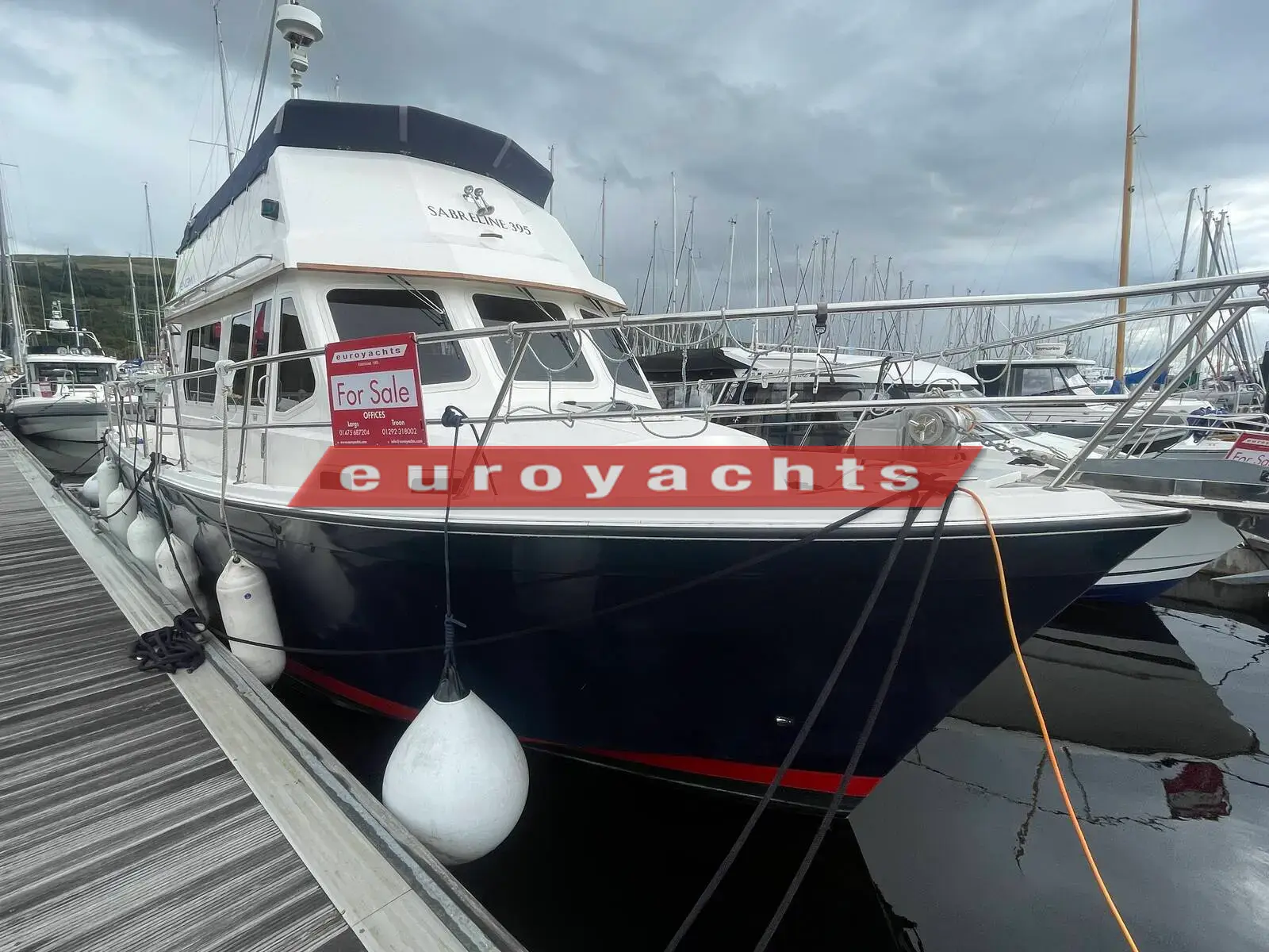 Northshore Yachts Sabreline 395 Trawler: port bow view of the white flybridge trawler with navy hull moored at a pontoon