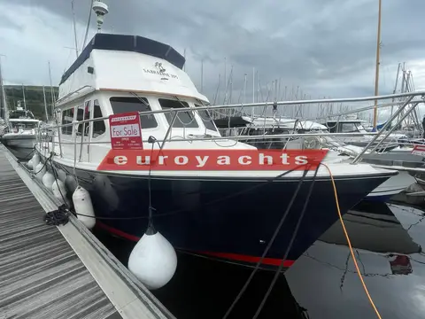 Northshore Yachts Sabreline 395 Trawler: bow quarter view alongside a wooden pontoon under cloudy skies