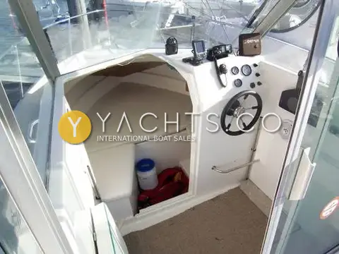 Ocqueteau 575: pilothouse interior with helm wheel, gauges, electronics and the cushioned v-berth forward
