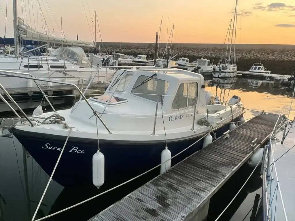 Orkney Boats Pilot House 20 Mk II: navy hull and white wheelhouse moored on a pontoon at sunset in a marina