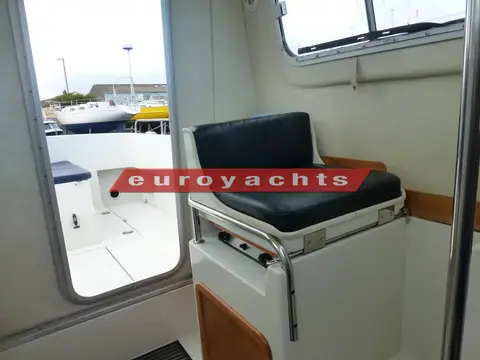 Orkney Boats Pilothouse 24: navigator's seat to port with black cushion beside the open door to the cockpit