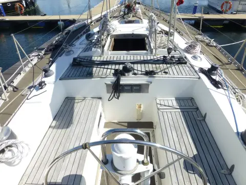 Oyster 435: cockpit looking forward from the wheel, teak-style seats and open engine hatch in the sole