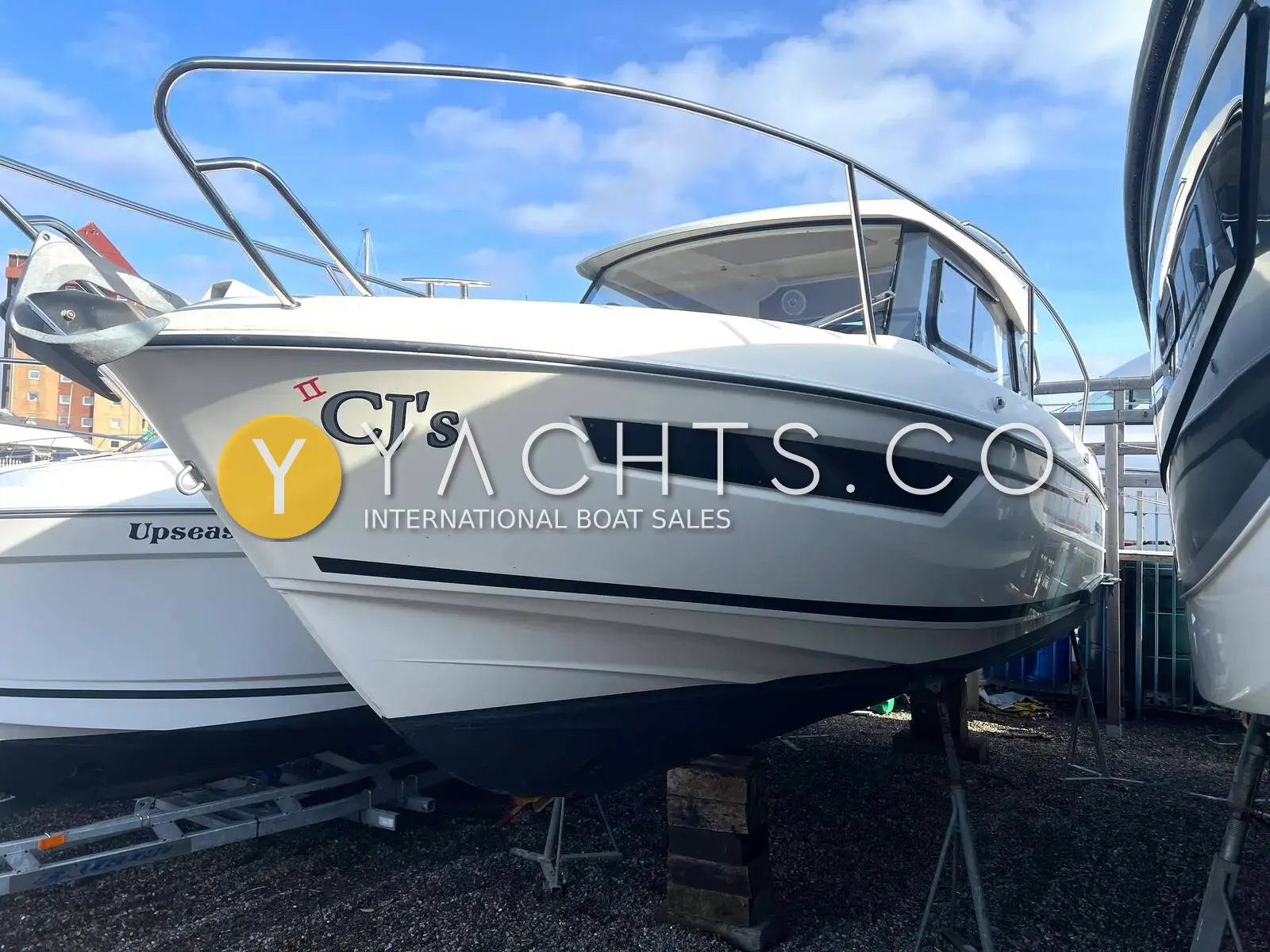Parker 750 CC: white hull with dark window band and stainless bow rail, ashore on stands in a boatyard