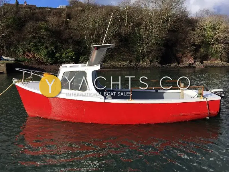 Pilot Plymouth Pilot 18: port side profile of the red hull and white wheelhouse on a mooring below a wooded bank
