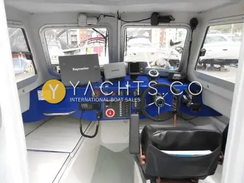 Pirate 21: helm inside the cuddy with blue dash, Raymarine display, wheel and black helm seat