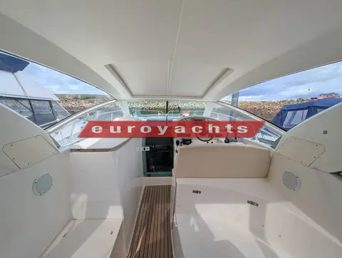 Prestige 30S: cockpit under the hard-top looking forward to the helm, white seating and teak sole