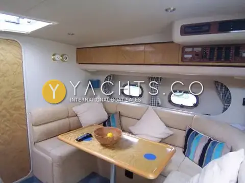 Princess 366: saloon with U-shaped cream seating, wooden table, portholes with checked curtains and systems panel
