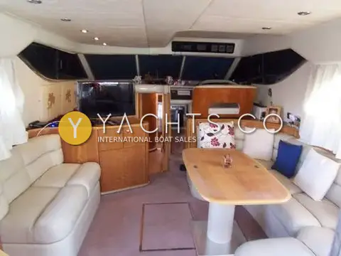 Princess 480 Flybridge: saloon with cream leather sofas, wooden table, high gloss wood cabinetry and TV facing forward