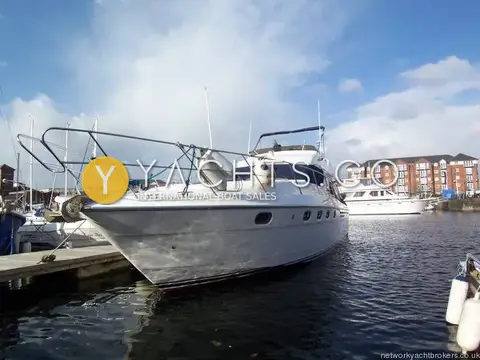 Princess 480 Flybridge: bow view of the cruiser on her berth with fenders on the pulpit and marina buildings behind