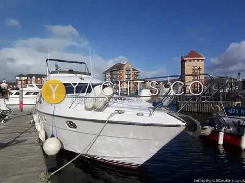 Princess 480 Flybridge: starboard bow view alongside the pontoon, fenders out, with a brick clock tower behind