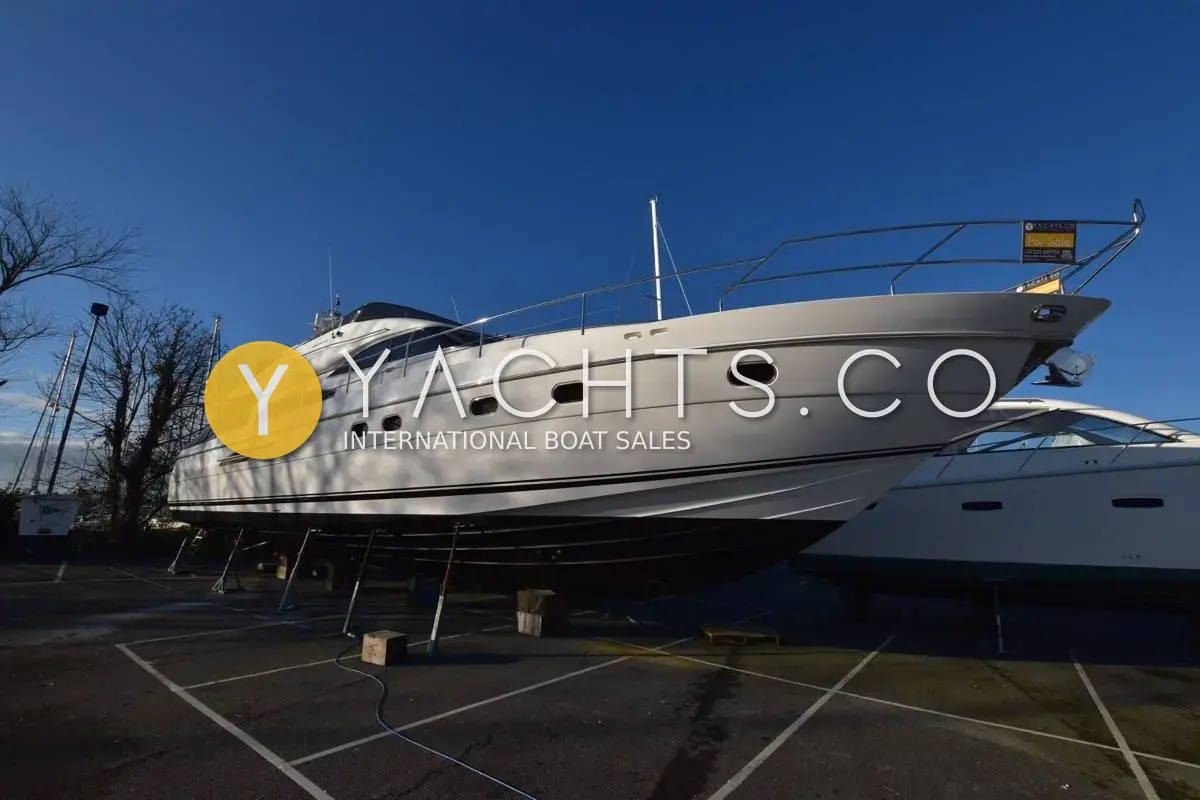 Princess 65: hull and flybridge seen from the bow while she sits ashore on stands in a boatyard