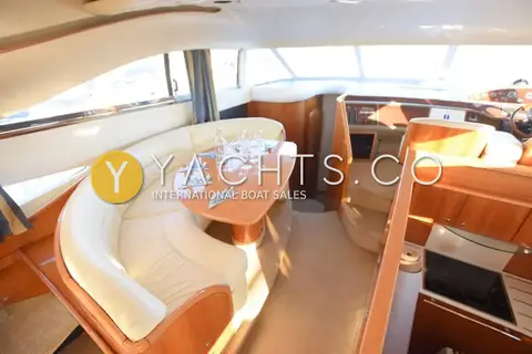 Princess 65: saloon dinette with cream U-shaped sofa, glossy cherry table and cabinetry by the windows