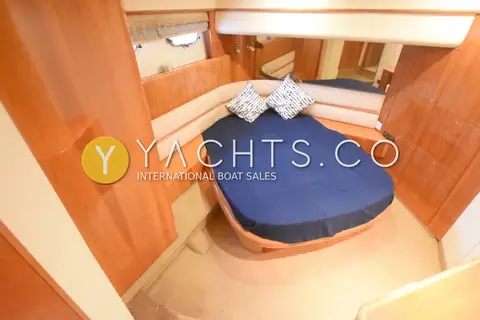 Princess 65: double cabin with navy bedspread, cushions and gloss cherry wood panelling