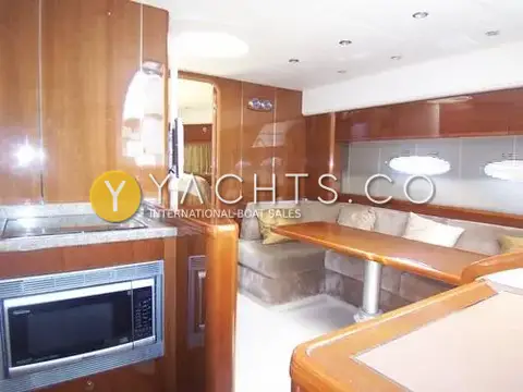 Princess V45: saloon and galley with cherry woodwork, microwave, hob and U-shaped seating round a table