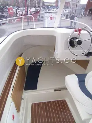 Quicksilver 500 Pilothouse: wheelhouse interior with steering wheel, blue and cream berth cushion and teak-style sole