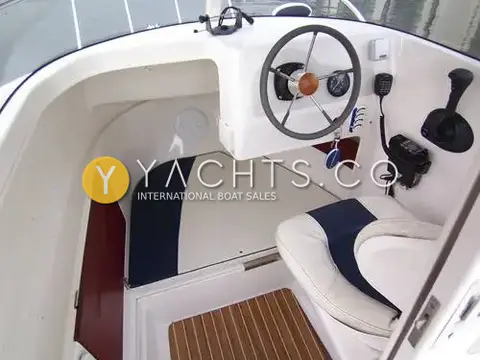 Quicksilver 500 Pilothouse: pilothouse interior with wheel, fold-away helm seat, VHF handset, throttle and forward seating