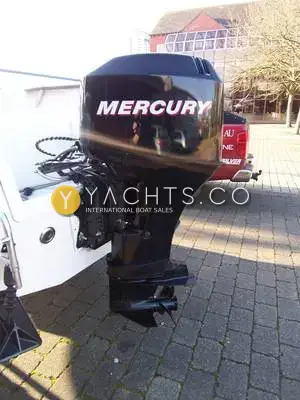 Quicksilver 500 Pilothouse: black Mercury outboard tilted up on the transom, ashore on a paved quay