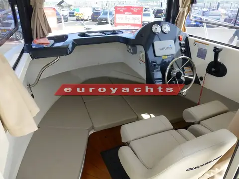 Quicksilver 605 Pilothouse: pilothouse interior with cream cushioned forward seating, helm wheel and two adjustable seats