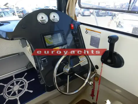 Quicksilver 605 Pilothouse: helm with steering wheel, two gauges, plotter screen and throttle lever on the side