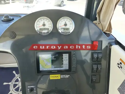Quicksilver 605 Pilothouse: close view of helm dash with two engine gauges, chartplotter and switch panel