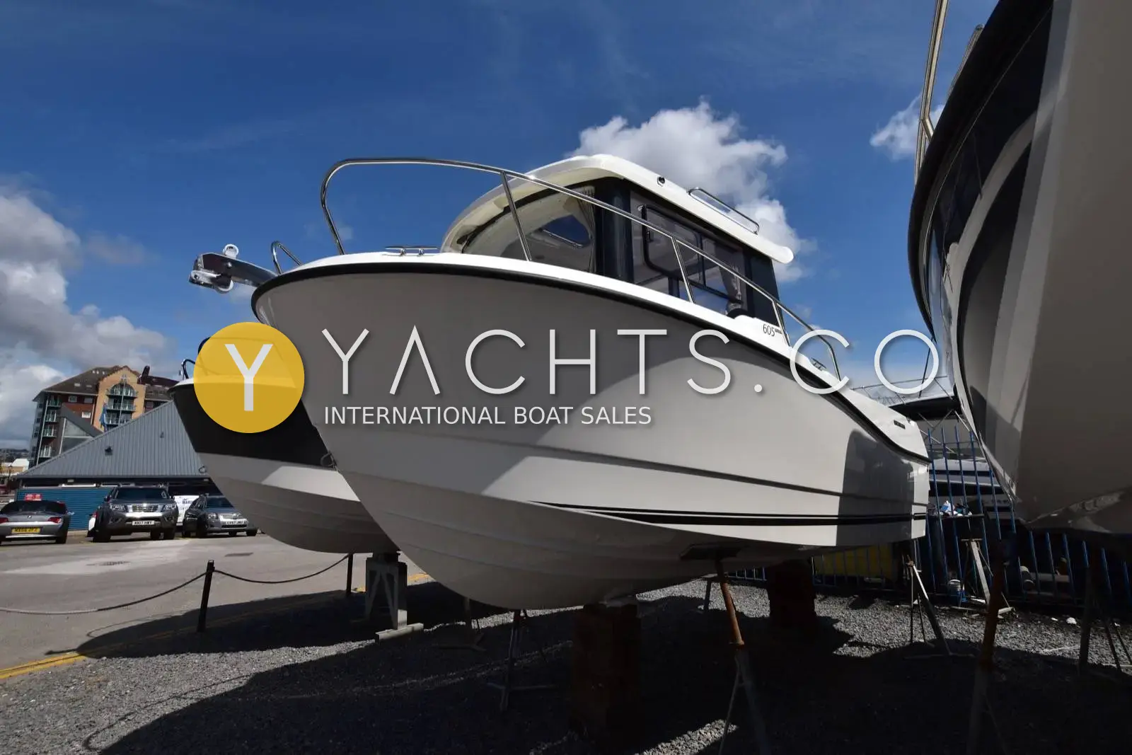 Quicksilver 605 Pilothouse - Smart Edition: white pilothouse hull ashore on stands at a marina boatyard under blue sky