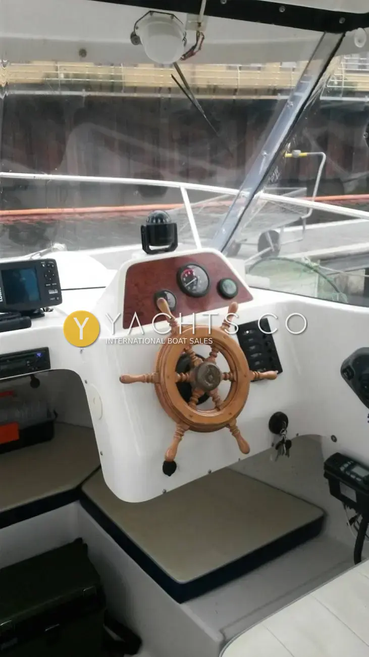 Quicksilver 620 Pilothouse: helm with wooden wheel, burr-effect gauge panel, compass, switch panel and fishfinder beside it