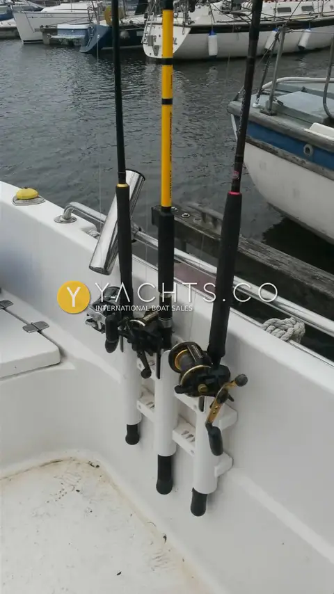 Quicksilver 620 Pilothouse: cockpit side with three rods and reels in a white rod rack, marina behind