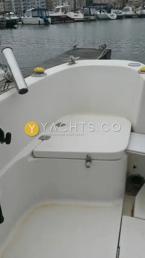 Quicksilver 620 Pilothouse: bow seating area with hinged locker lid and stainless rod holder on the gunwale