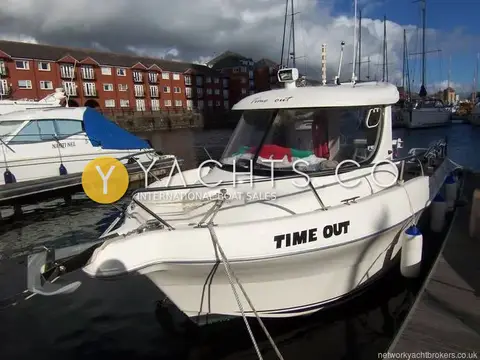 Quicksilver 640 Pilothouse: bow view of the white hull named Time Out, moored in a marina by red-brick flats