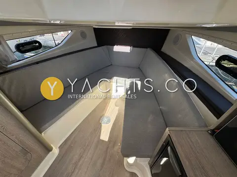 Quicksilver 875 Sundeck: forward dinette in grey upholstery with portlights on both sides