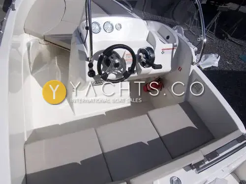 Quicksilver Activ 455: cockpit looking forward to the console helm, with three-seat aft bench cushions and fire extinguisher